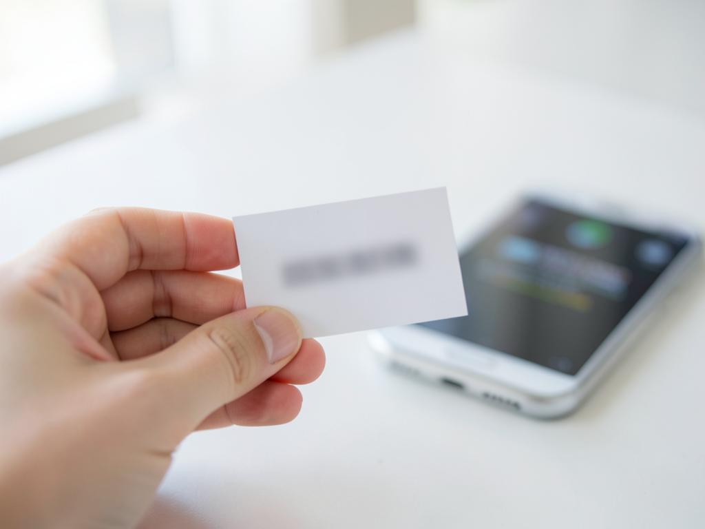 Holding the printed activation code card beside a phone